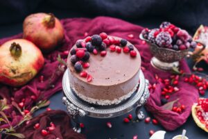 A beautiful Chocolate Raspberry Cake with berries and pomegranate seeds scattered arround