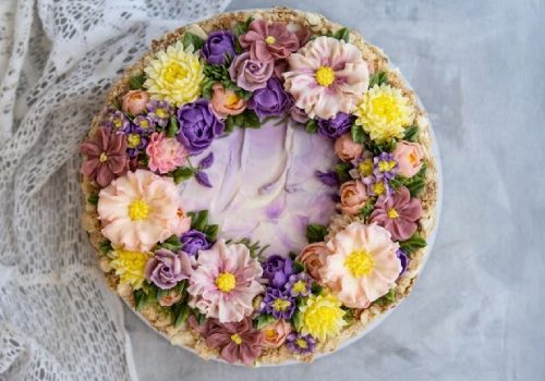 An elegantly decorated cake adorned with a variety of edible flowers in pastel hues
